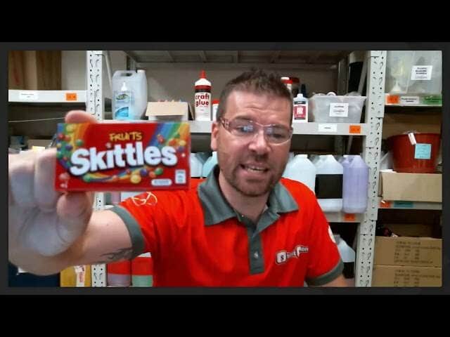 A screenshot of a man holding a Skittles box.