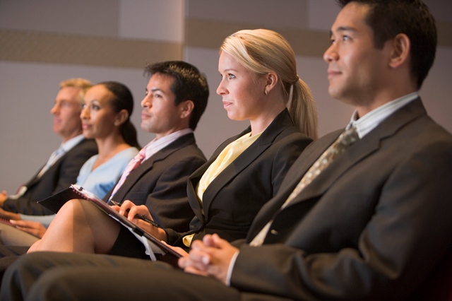 Five businesspeople sitting in presentation room w