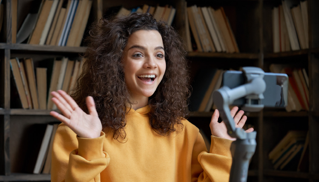 A video creator records a sponsored ad in front of her bookshelf after learning about the best content monetization strategies.