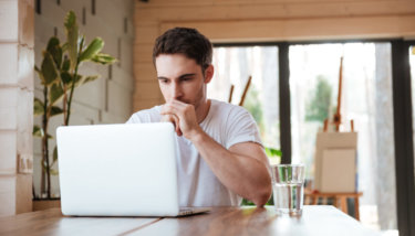 An image of a man browsing the internet in search for the best online community platforms for his membership business.