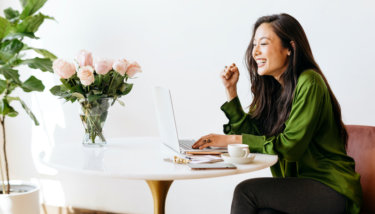 A woman looks gleefully at her computer, indicating she learned how to grow a Facebook Group.