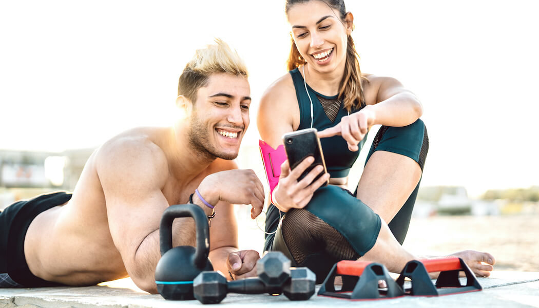 Young couple at the beach working out and learning how to make money on Instagram as fitness influencers.