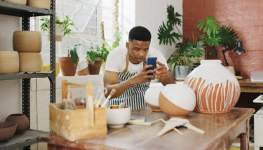 A man photographs ceramic vases to add to his Instagram shop.