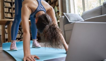 A woman follows along to a live streamed yoga class, indicating the instructor has put to use ways to grow an online fitness community.