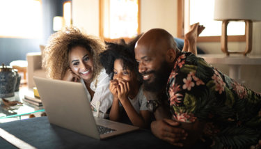 A family sits in front of the computer while watching a video-on-demand service.