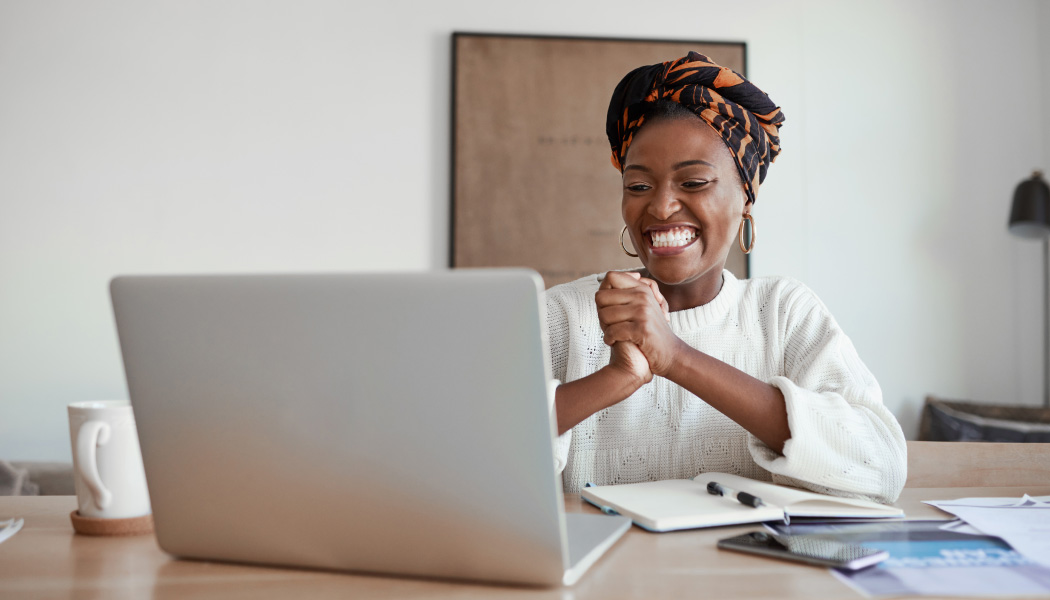 A woman smiles in front of her computer while choosing a membership pricing strategy.