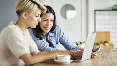 2 women use a laptop to research Facebook Group alternatives for their online community.