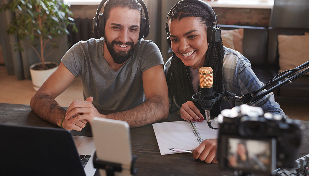 Two people sit in front of cameras while recording a live stream