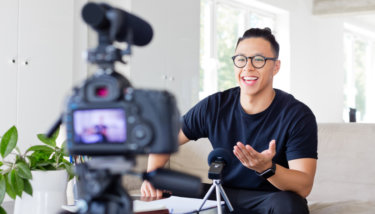 A man talks in front of a camera while recording a video for YouTube.