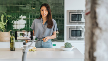 A woman records a video in her kitchen after finding the perfect platform among the many Zype alternatives.