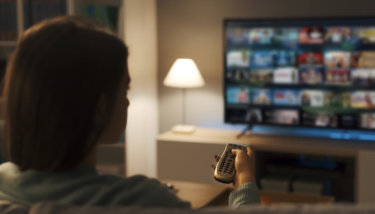 A woman is browsing through her smart TV app library from one of the best OTT platforms.