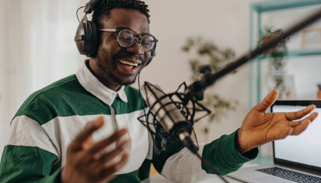 A man talks in front of a microphone while recording a live stream.