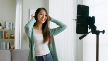 A woman smiles in front of the camera while recording a video.