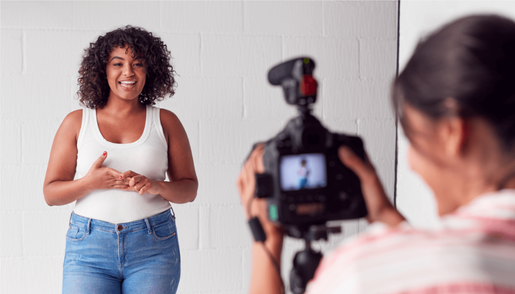 A woman records another woman with a camera in a studio.