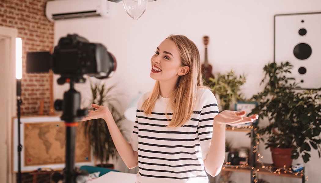 A woman stands in front of her camera while recording a video for her platform.