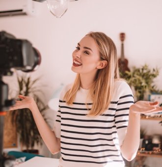 A woman stands in front of her camera while recording a video for her platform.