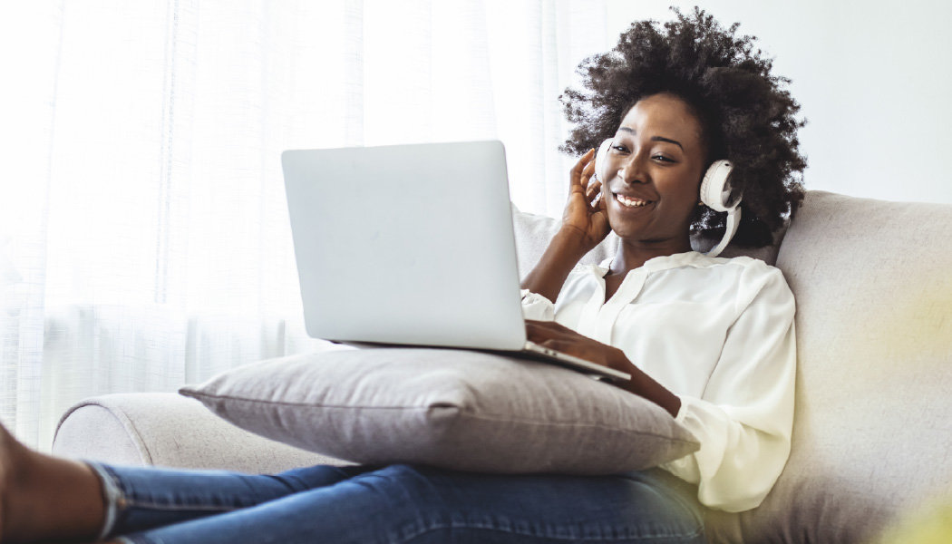 A woman watches content on her computer through the Apple TV app.