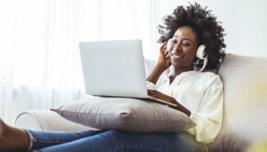 A woman watches content on her computer through the Apple TV app.