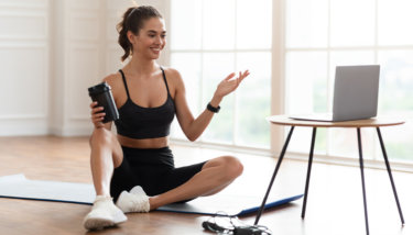 A woman sits in front of her computer ready to teach a fitness class on her membership site platform.