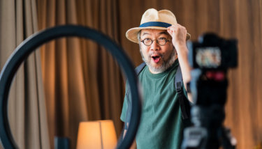 A man records a video of himself trying out hats.