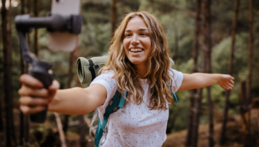 business model for online education A woman holds a camera and records a video while hiking