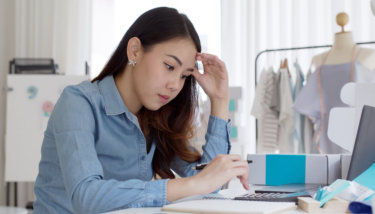 A image shows a woman business owner trying to figure out how to remove bottlenecks in her membership business to increase efficiency and improve results.