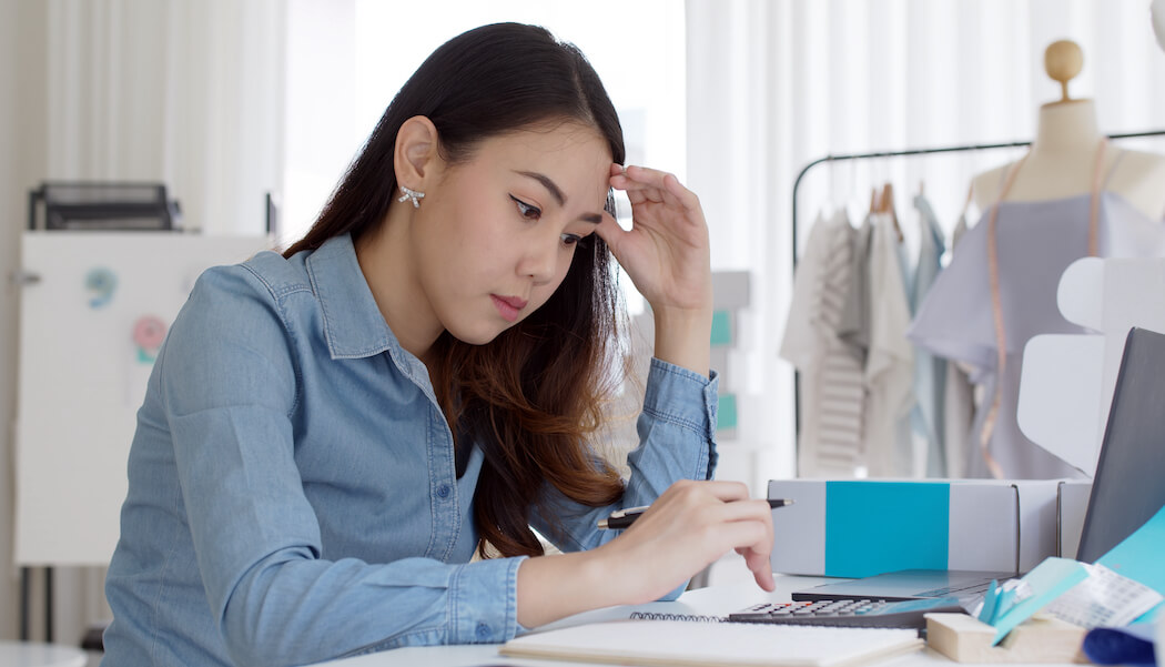 A image shows a woman business owner trying to figure out how to remove bottlenecks in her membership business to increase efficiency and improve results.