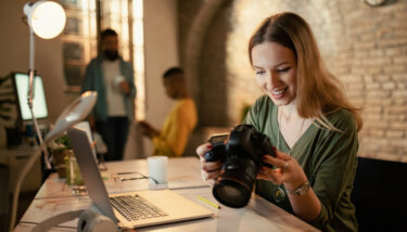 Happy freelancer looking at photos on camera while working late in her studio.