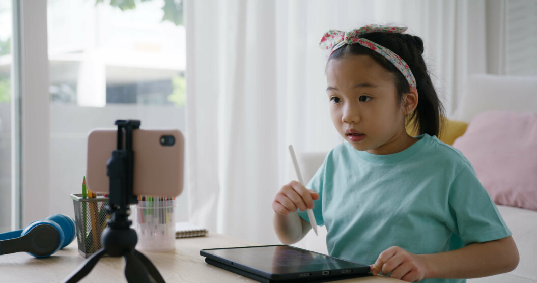 A young girl engaging with kids' content on a tablet while recording herself for YouTube Kids, showcasing a modern approach to interactive learning and content creation made for kids.