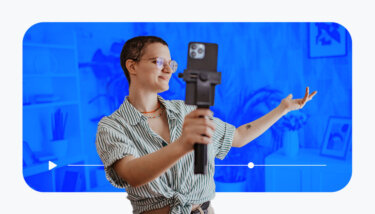 Creator talking to their phone on a mobile tripod with plants and a bookshelf behind them. Blue overlay with a video progress bar and play button.