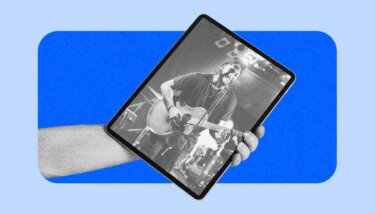 Blue stylized arm holding a tablet with a person performing for an audience with a guitar and microphone