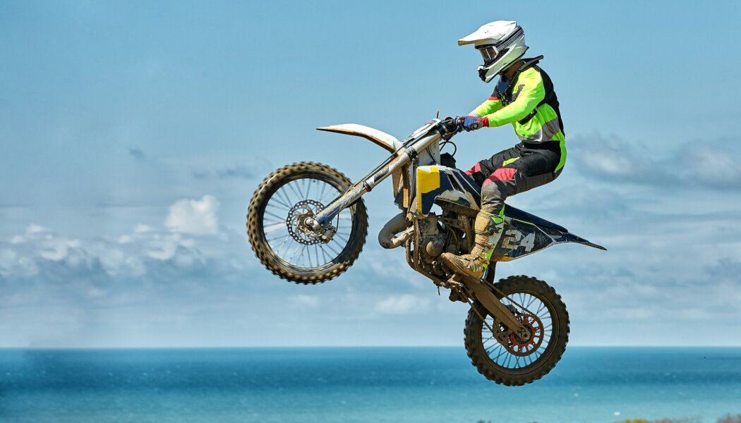 Extreme sports, motorcycle jumping. Motorcyclist makes an extreme jump against the sky. Film grain