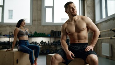 Portrait of young adult sports people having rest while sitting on fitness box