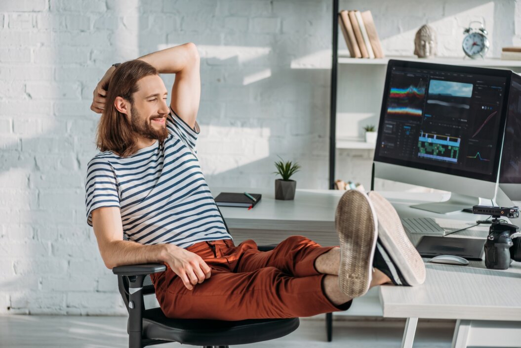 happy filmmaker resting near computer monitors in studio