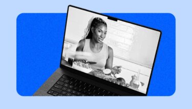 A woman live streaming and waving a camera on a couch in a living room.