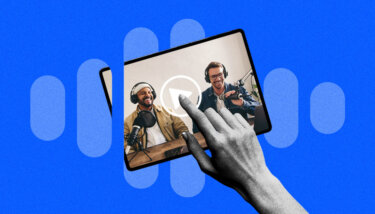 Hand touching a play button on a tablet, showing two content creators laughing into a mic.